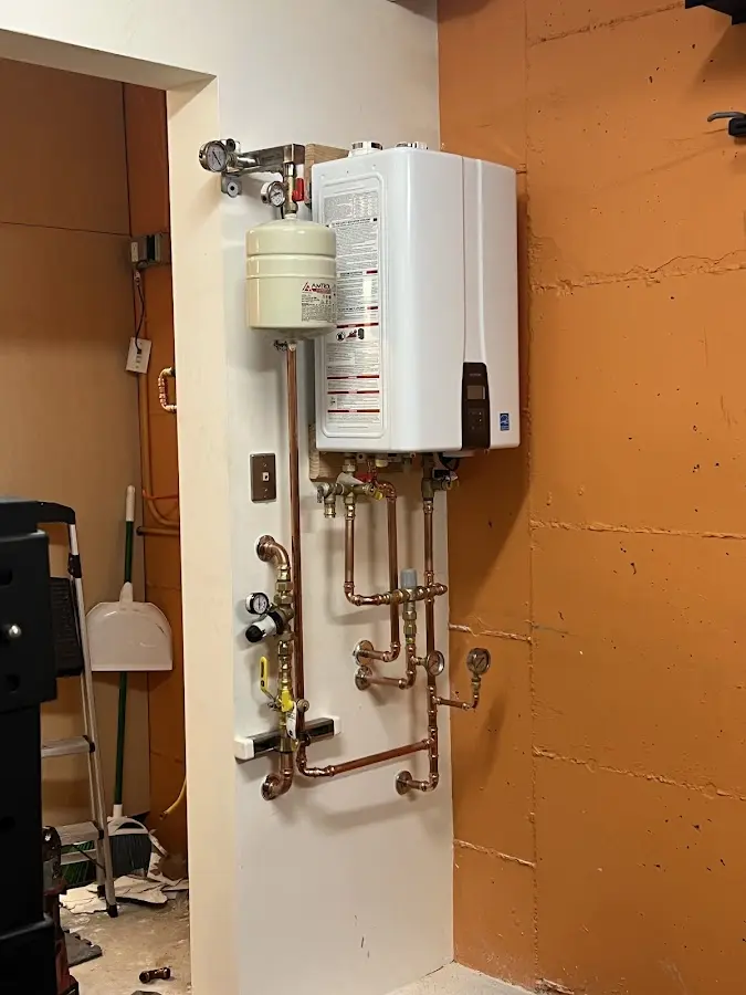 Plumbing technician inspecting water heater connections in Dennis